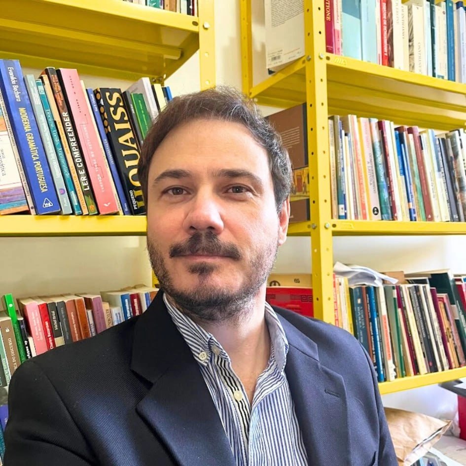Prof. Mendes - Melliandro Mendes Galinari em frente a uma estante de livros